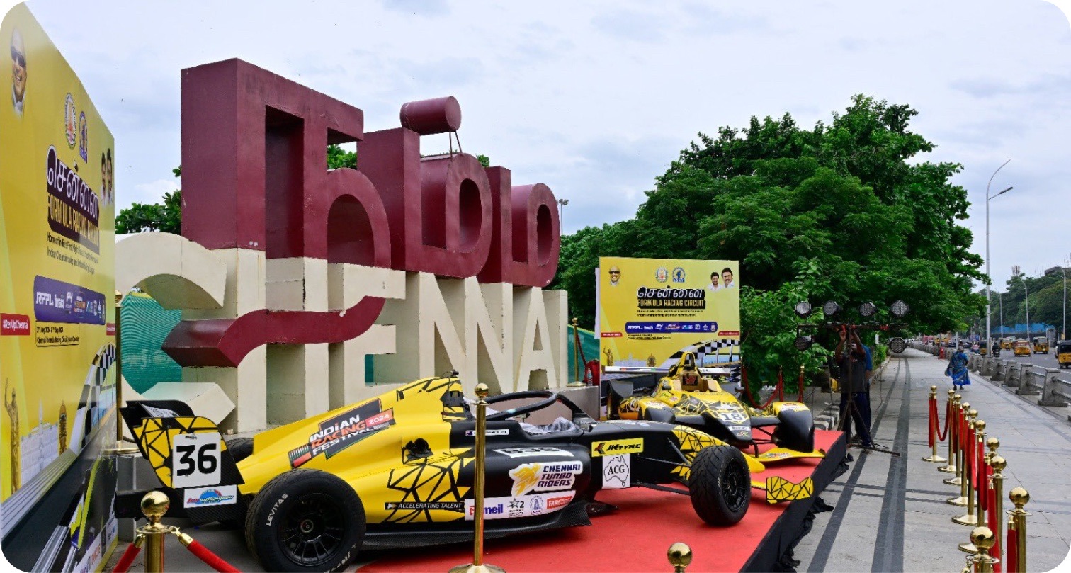 Yellow Formula 4 cars displayed in front of a large Chennai sign.
