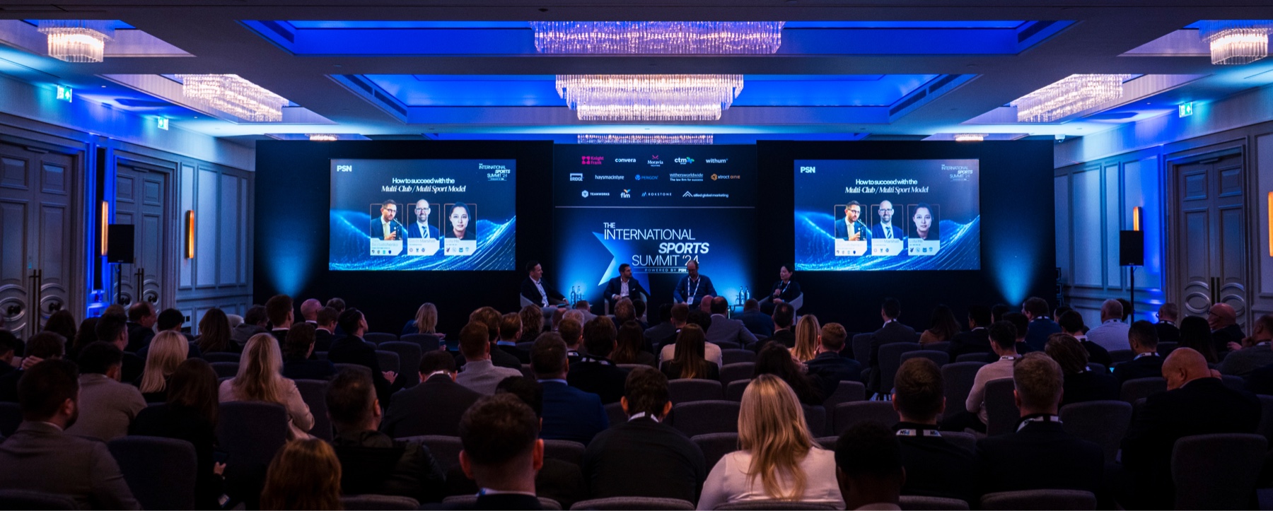 Audience seated in front of a lit stage at the International Sports Summit.